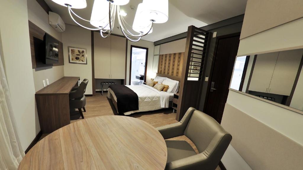 ein Hotelzimmer mit einem Bett, einem Tisch und Stühlen in der Unterkunft Klein Ville São Leopoldo in São Leopoldo