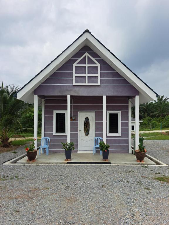 una casita morada con dos sillas y una puerta en Teratak Sumayyah - For Islam Only - Pondok Lenggong, en Kampong Banggol Belimbing