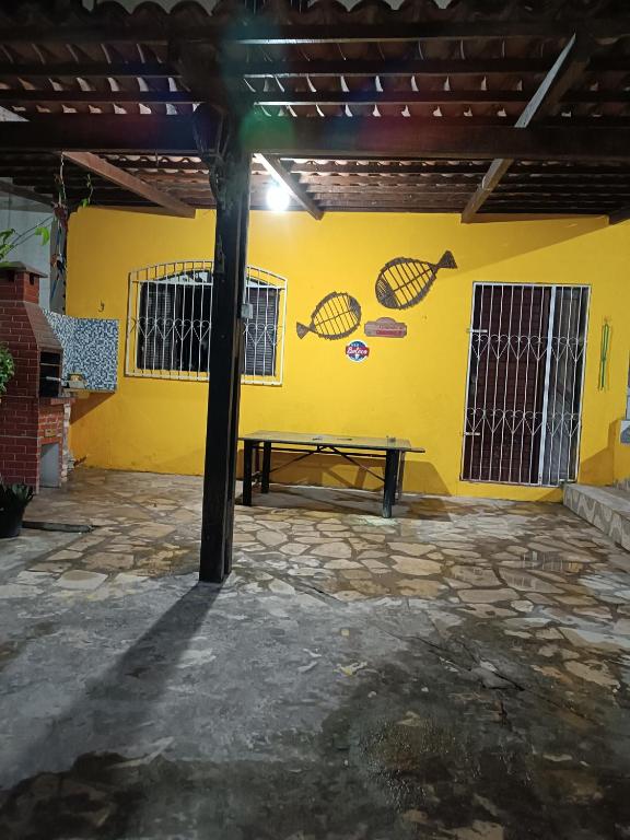 a patio with a picnic table against a yellow wall at Recanto do polly in Lucena