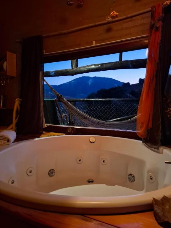a bath tub sitting in front of a window at Pousada Vale Monte Azul in Santo Antônio do Pinhal