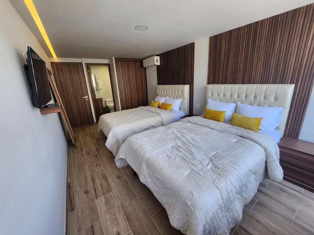 a hotel room with two beds and a flat screen tv at 21 Bella habitación Consulado in Guadalajara