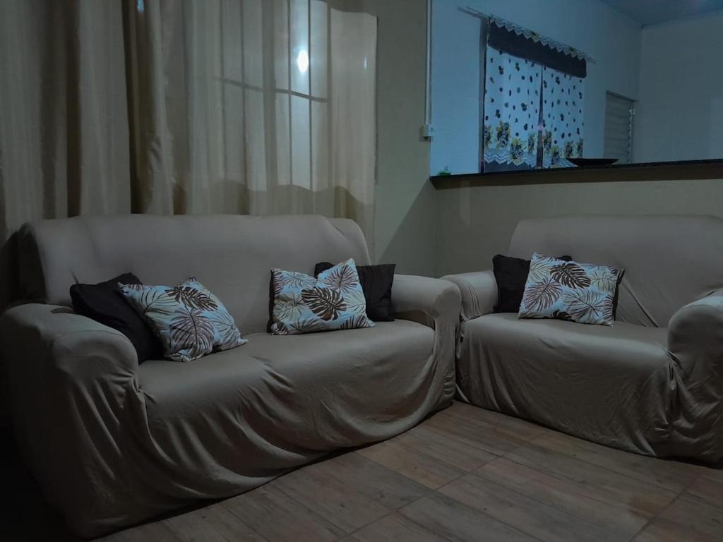 a couch with pillows on it in a living room at Chácara pedacinho do paraíso in Cesário Lange