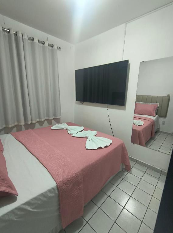 a bedroom with a bed with a tv on the wall at Ap confortável e Aconchegante in Petrolina