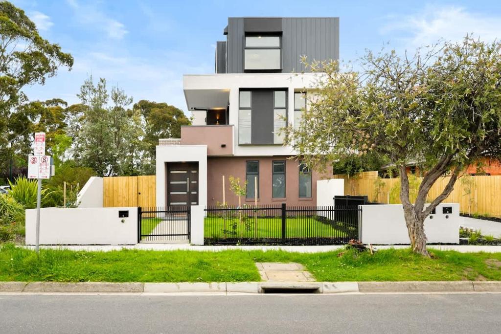 ein Haus mit einem Zaun vor einer Straße in der Unterkunft Amazing Modern Townhouse at Heart of Mount Waverley in Mount Waverley