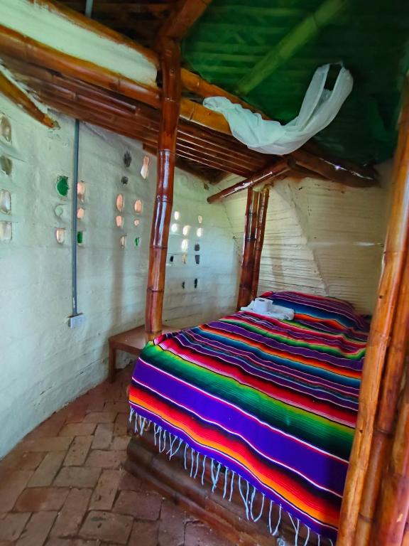 a bed with a colorful blanket on it in a room at Hospedaje casa en el Árbol in Moniquirá