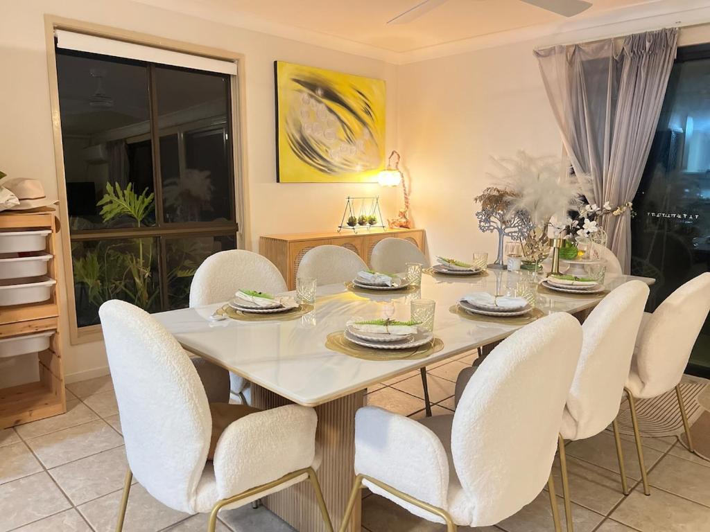 a dining room with a table and white chairs at Tranquil Hideaway in Mudgeeraba in Gold Coast