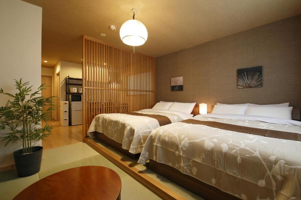 a bedroom with two beds and a table at Kamon Inn Uji 2-D in Uji