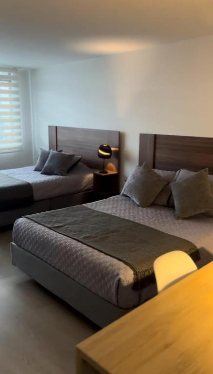 Un dormitorio con dos camas y una mesa con lámpara. en Apartahotel La Arboleda HC, en Manizales
