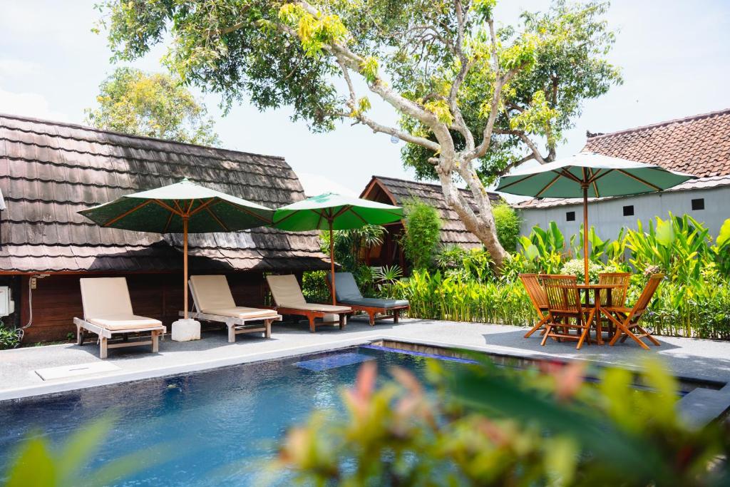 a group of chairs and umbrellas next to a swimming pool at Kubu Kak Dudung Villas in Jimbaran