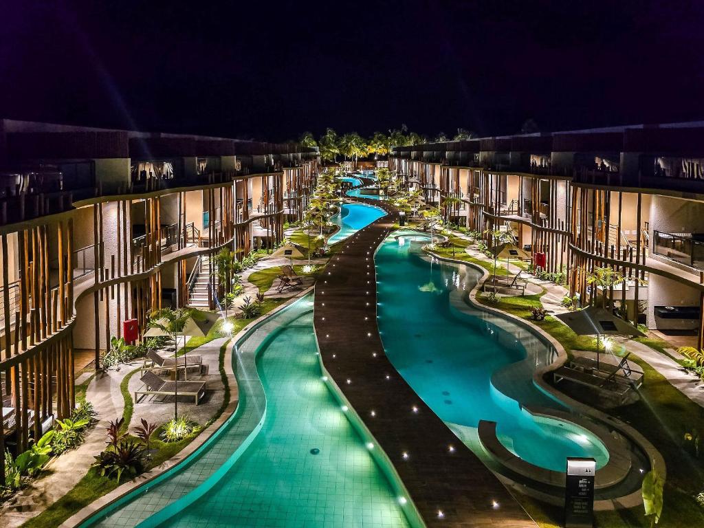 - une piscine vide dans un complexe la nuit dans l'établissement Flat premium no Naay Villas Boutique para 8 pessoas, à Tatuamunha