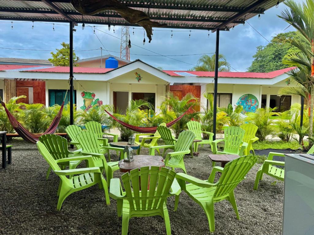 a group of green chairs and tables in front of a building at Kalunay Hostel - Breakfast included in Puerto Viejo