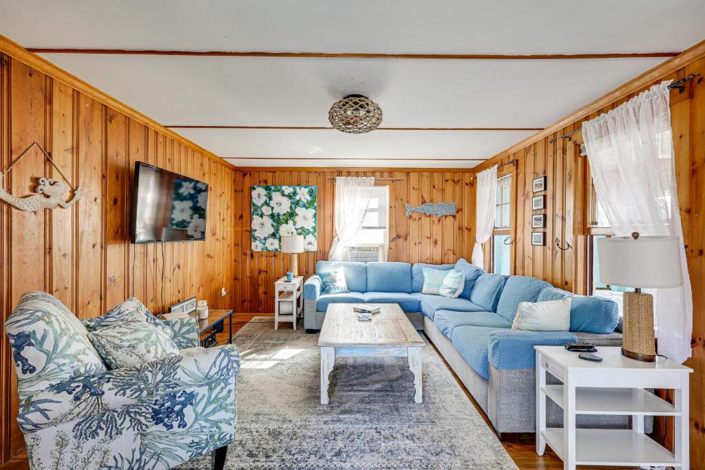 ein Wohnzimmer mit einem blauen Sofa und Holzwänden in der Unterkunft 1 Block to Humarock Beach Pet-Friendly Cottage in Fourth Cliff