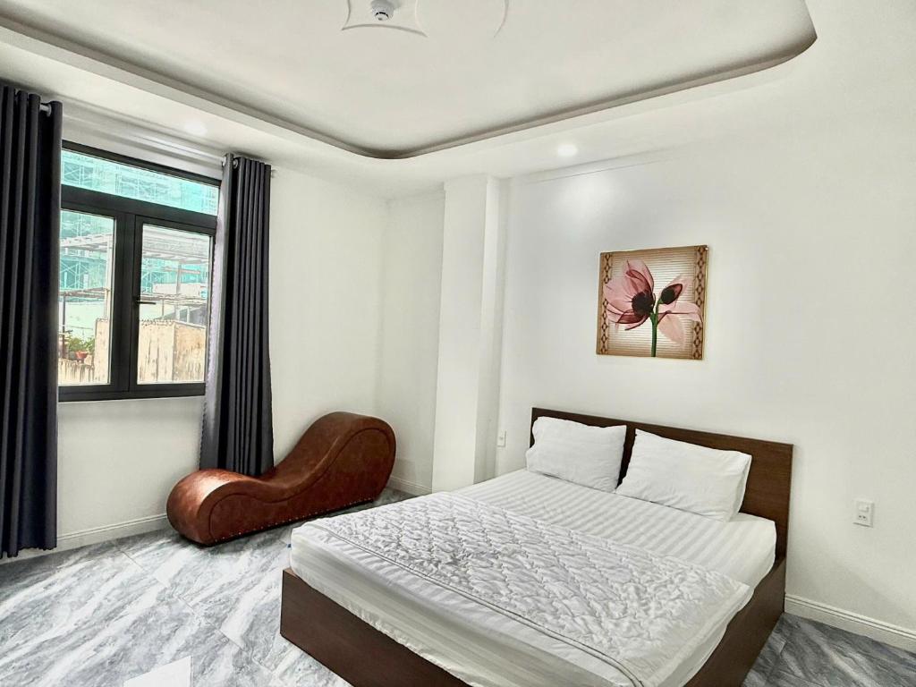 une chambre blanche avec un lit et une chaise dans l'établissement Hotel Bảo Bảo, à Thuan An