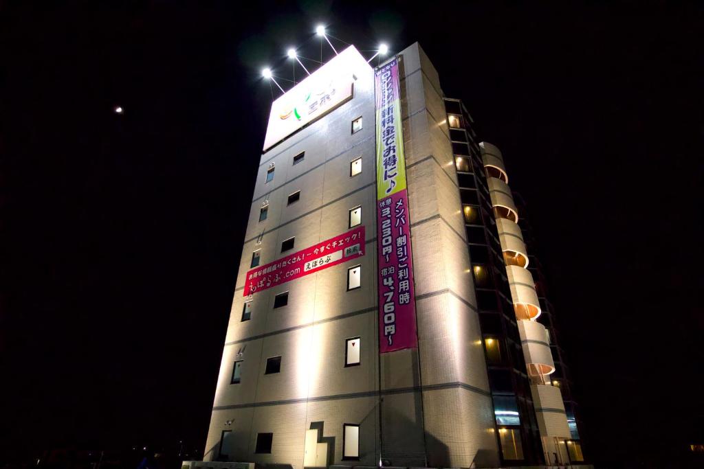 a tall building with signs on it at night at ホテルエポーAdult onlyー in Toyokawa