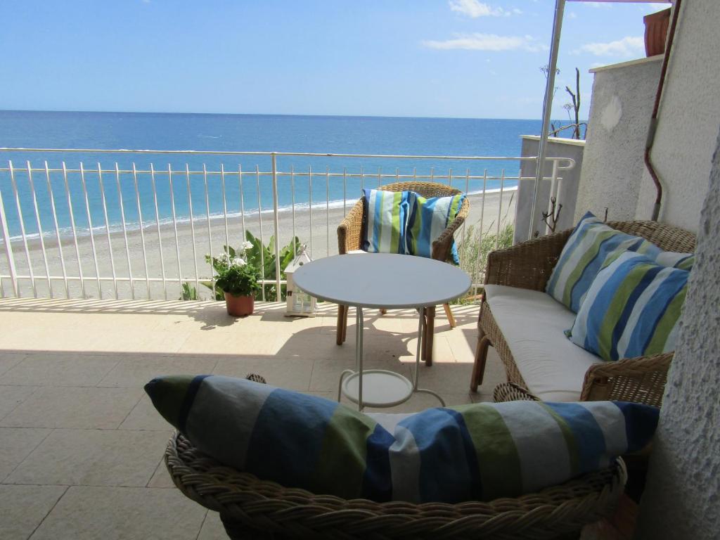 un patio con sofá, mesa y la playa en Appartamento mare mare, en Forza dʼAgro