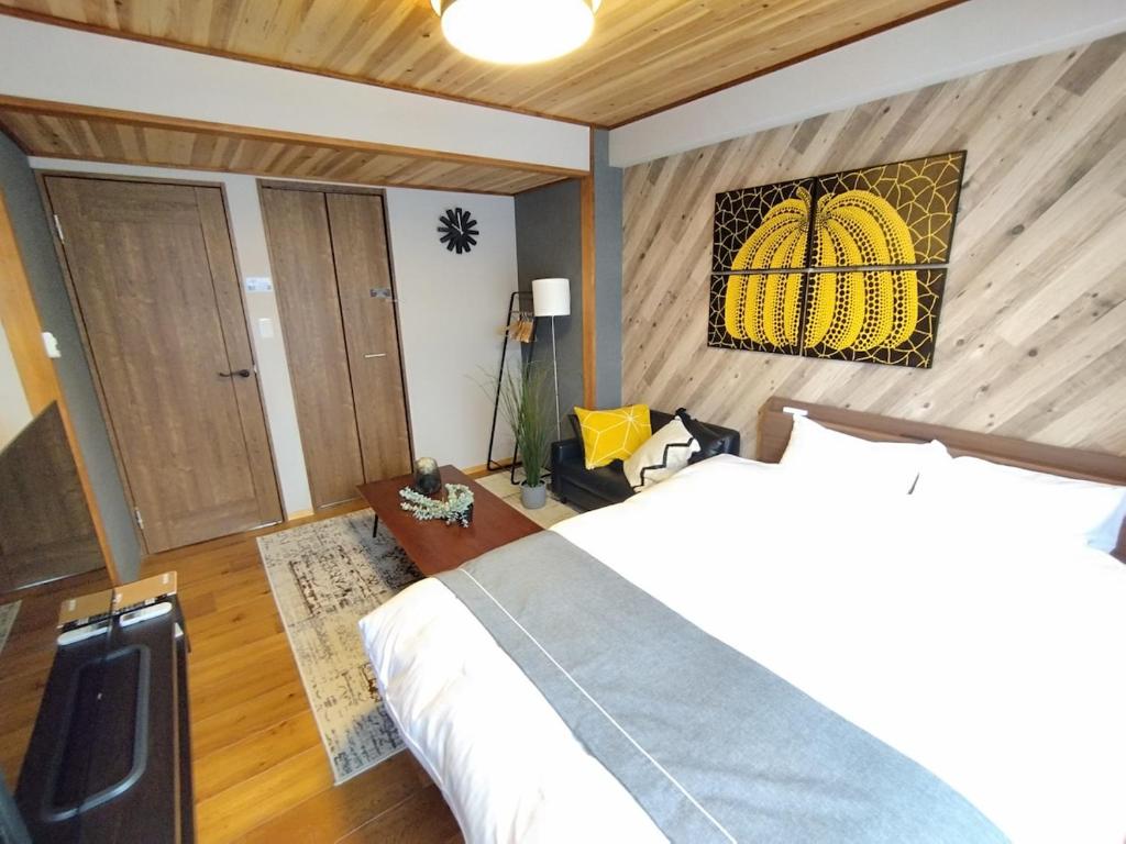 Ein Schlafzimmer mit einem Bett und einem Bild eines Kürbisses an der Wand in der Unterkunft ゲストハウスsimasima古馬場301 in Takamatsu