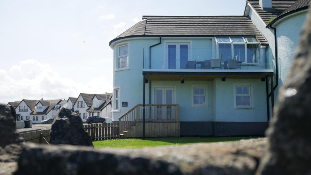 a white house with a fence in front of it at SeaBreeze - Portballintrae in Portballintrae