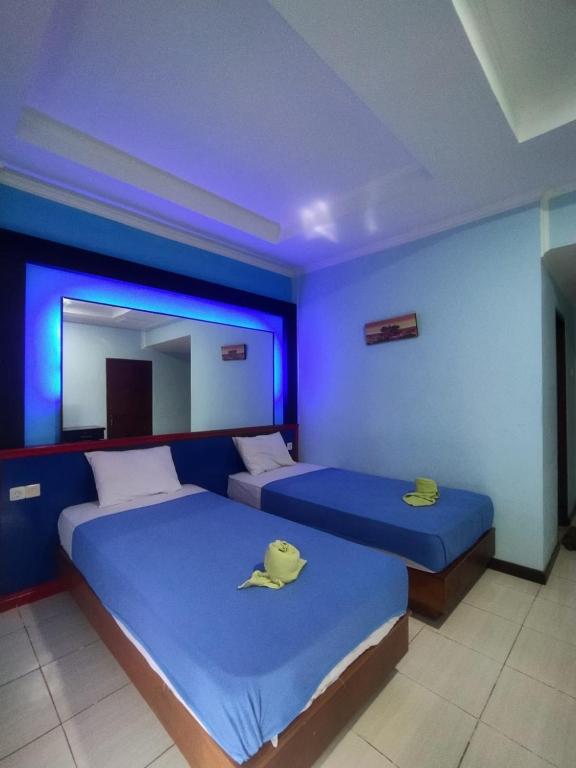 two beds in a room with blue lighting at Citepus Indah Hotel in Citepus