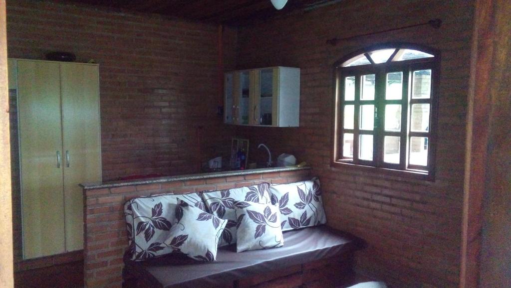 a room with a bench with pillows and a window at Sítio Leotaianne -Apenas um Chalé exclusivo no sitio in Itaboraí
