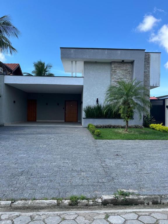 a house with a palm tree in front of it at Casa térrea moderna em condomínio in Bertioga