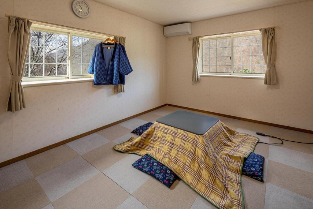 a room with a blanket on the floor and two windows at 山の湯 in Wada