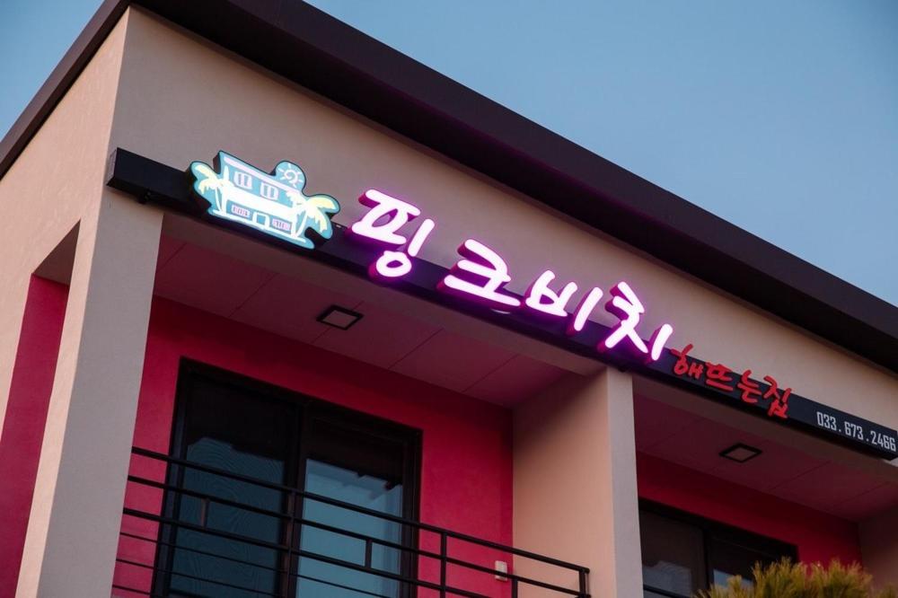 a building with a neon sign on top of it at Hajodae Pink Beach Pension in Yangyang