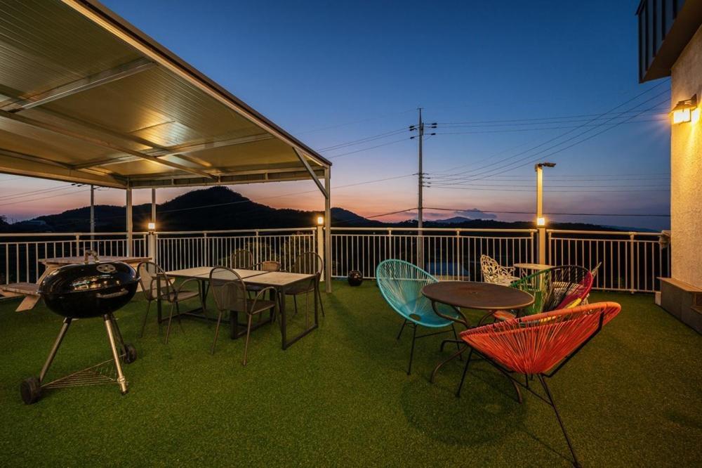 a deck with a table and chairs and a grill at Yeosu Little Forest Pension in Yeosu