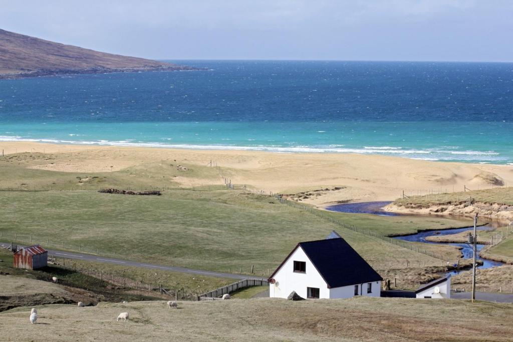 a white house on a hill next to the ocean at Otter Cottage in Manish