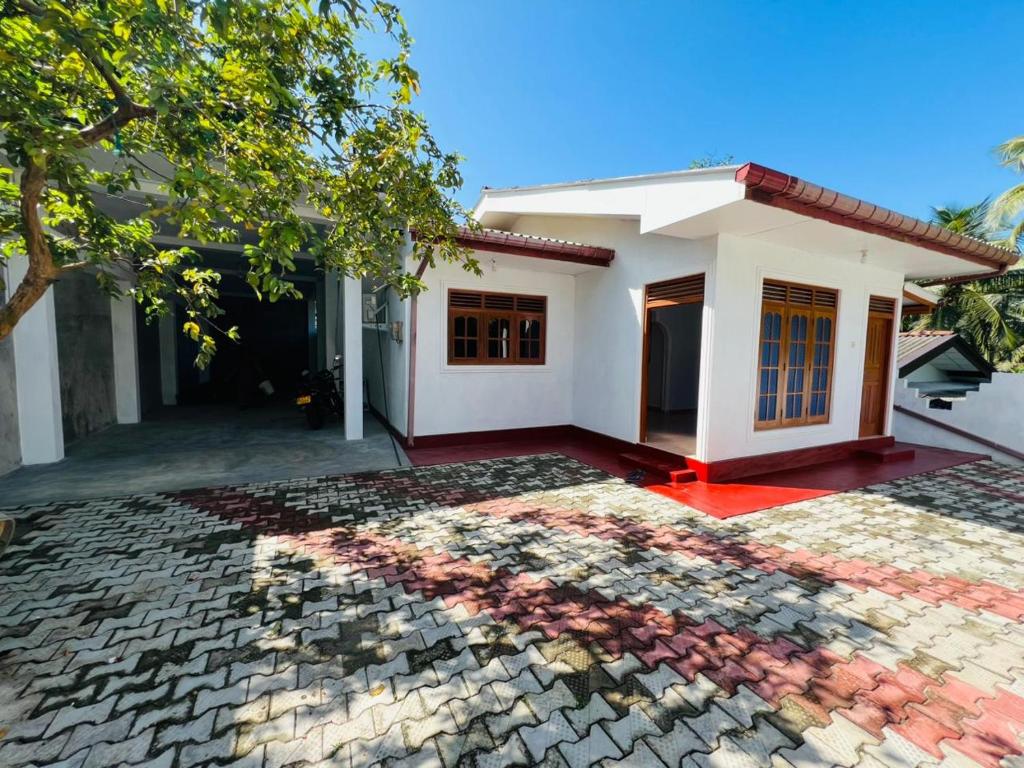 a small white house with a stone driveway at Ranathunga Guest House in Ginimellagaha West