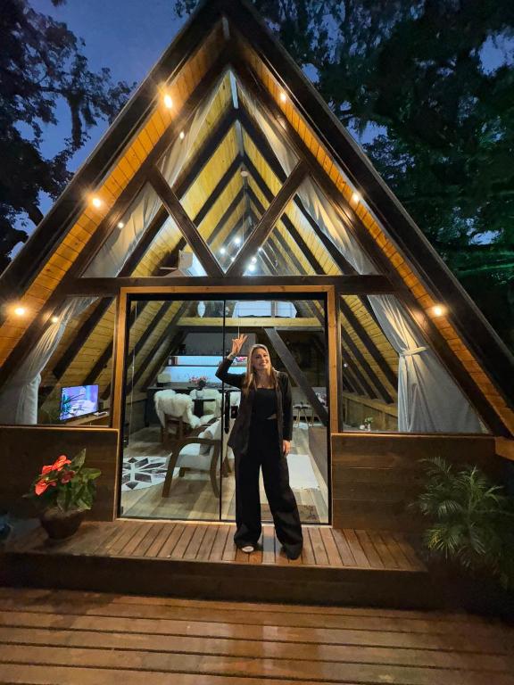 a woman is standing in the front of a house at A-Frame da Lagoa in Imaruí