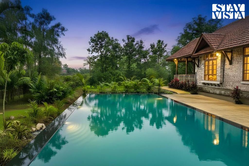 a swimming pool in front of a house at StayVista at Orchard by the River with Bonfire, BBQ in Karjat