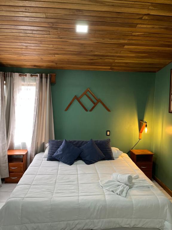 een slaapkamer met een groot wit bed en een groene muur bij Monteverde Guesthouse in Monteverde Costa Rica