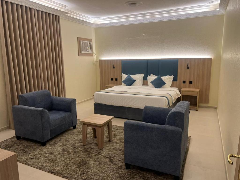 a hotel room with a bed and two chairs at أجنحة أحد للشقق المفروشة in Al Madinah