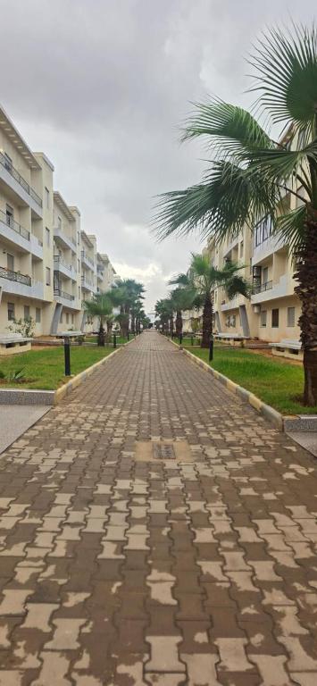 an empty street with palm trees and buildings at appartement sable dor in Mohammedia