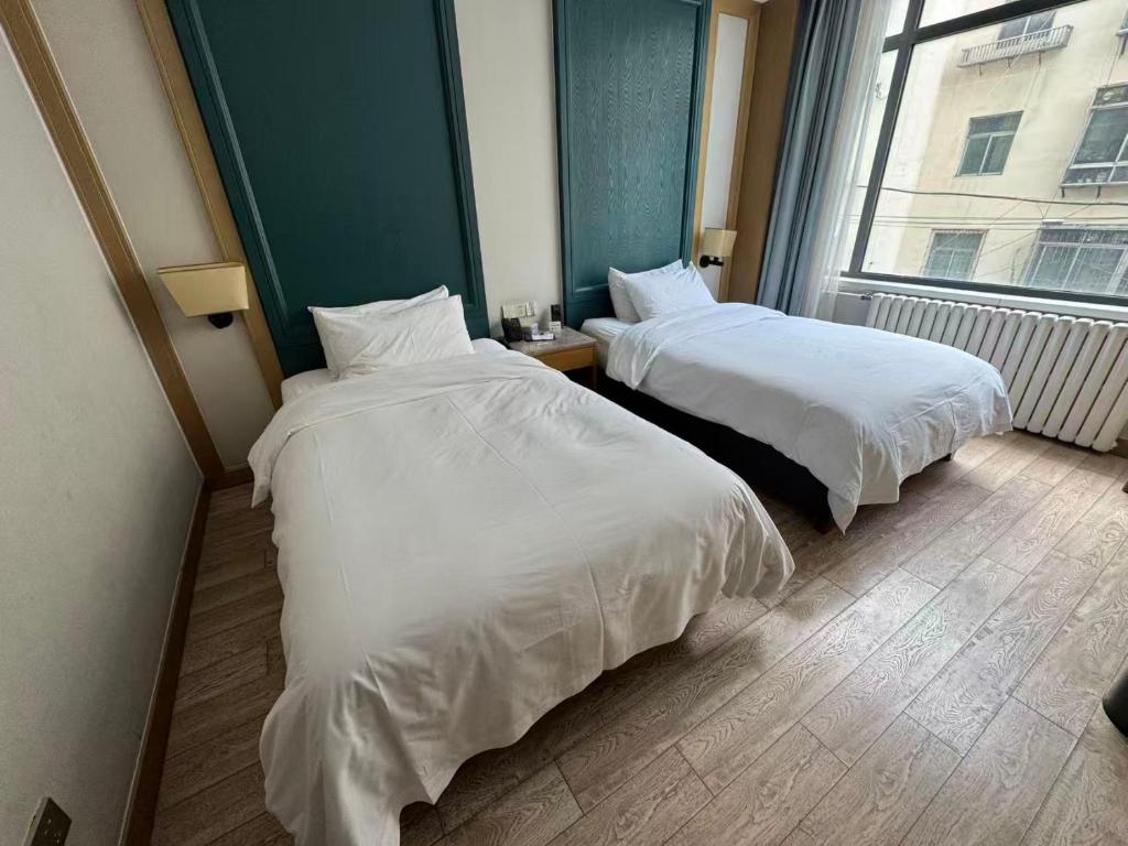 een hotelkamer met twee bedden en een raam bij Ward Hotel Jinan Harmony Plaza Qilu Children's Hospital Branch in Jinan