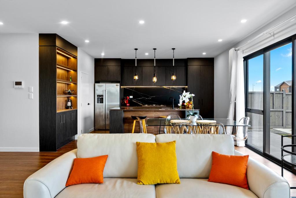 a living room and kitchen with a white couch and orange pillows at Its a bit country and a bit town in Karaka