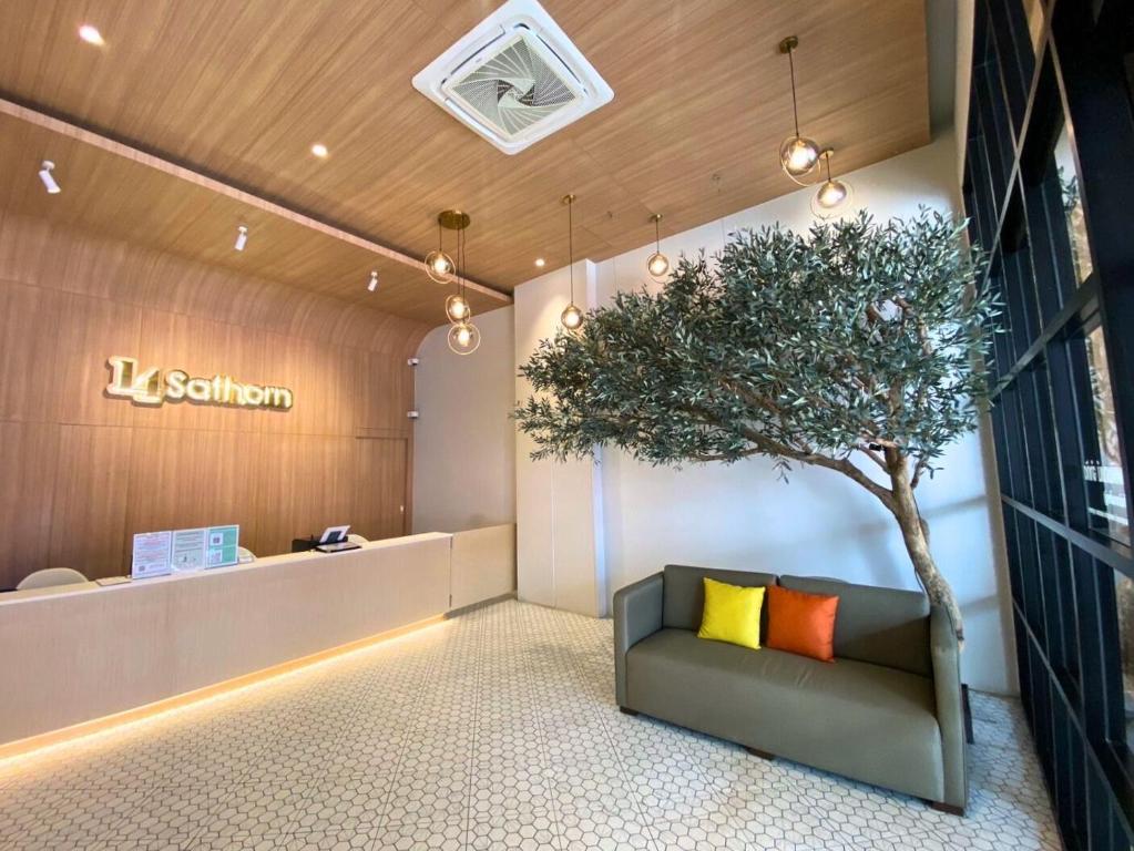 a tree in the middle of a lobby with a couch at 14 Sathorn Hotel in Bangkok