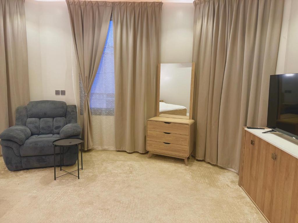 a living room with a chair and a television at فيلا آنسي Villa Annecy in AlUla