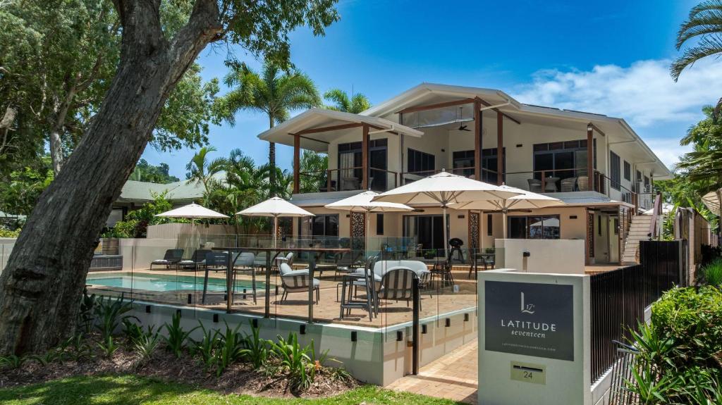 a house with a pool and tables and umbrellas at Latitude 17 - Suite 1 in South Mission Beach