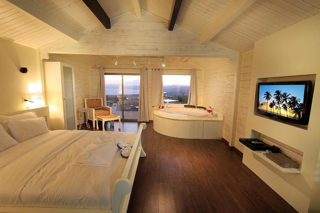 Un dormitorio con una cama, una bañera y un televisor. en נופי גמלא, en Ma'ale Gamla