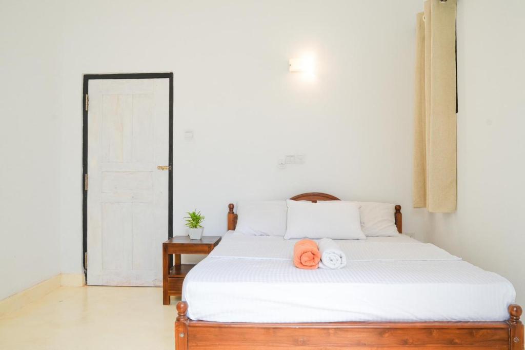 Marakuja House في Nikawatawana: غرفة نوم بها سرير أبيض عليه قبعة برتقالية