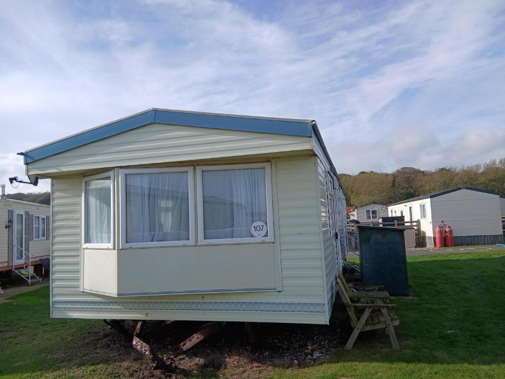 uma pequena casa está sentada na grama em Charming 6 Berth Caravan With Decking By The Beach In Suffolk Ref 40107Nd em Gunton