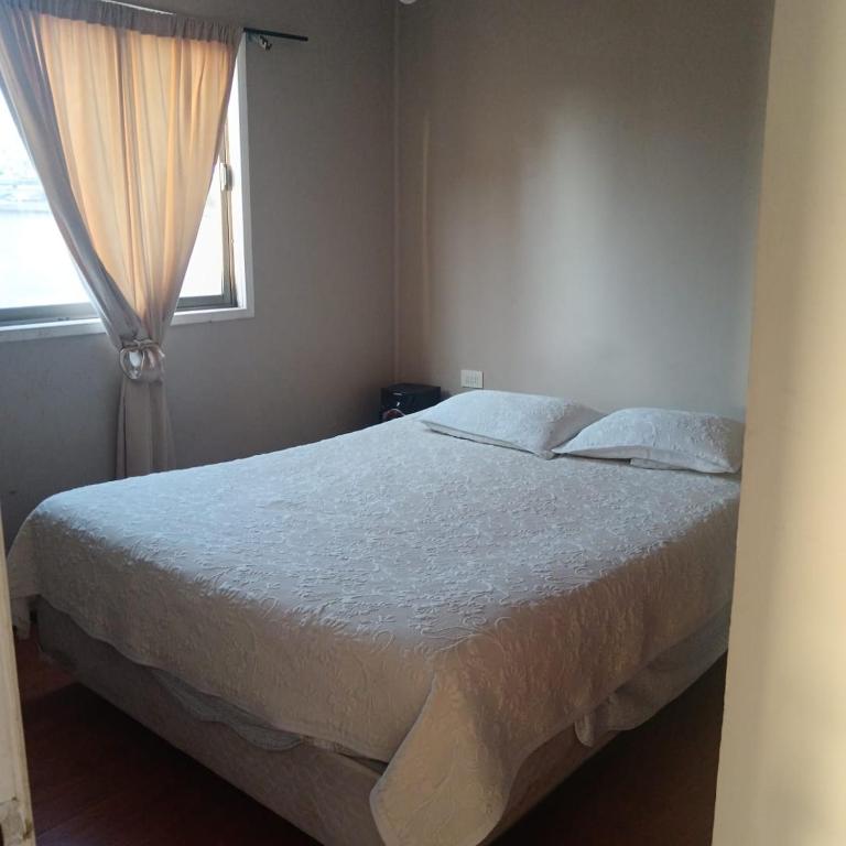 a bedroom with a large bed with a window at Base Rebelde 77 in Quilpué