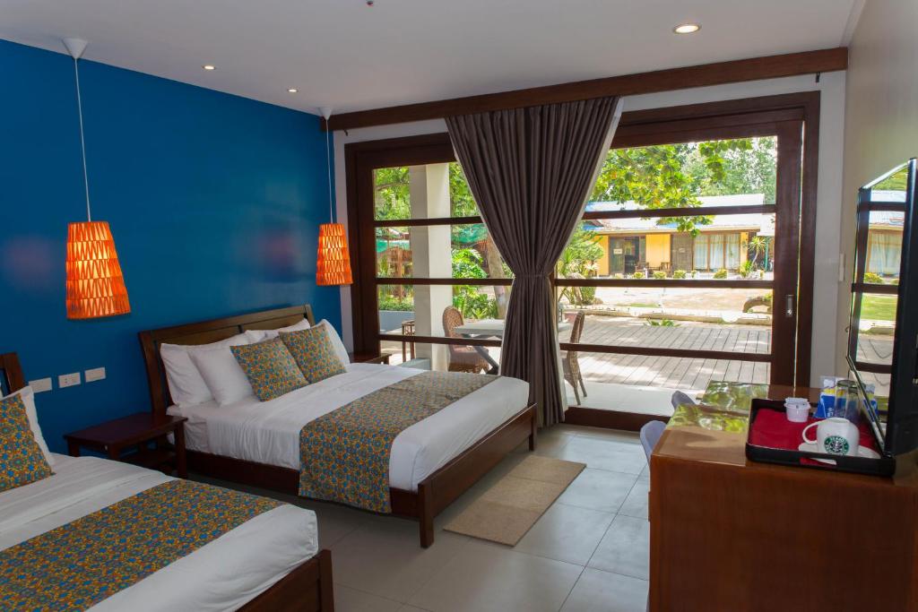 a hotel room with two beds and a window at Karancho Beach House in Mactan