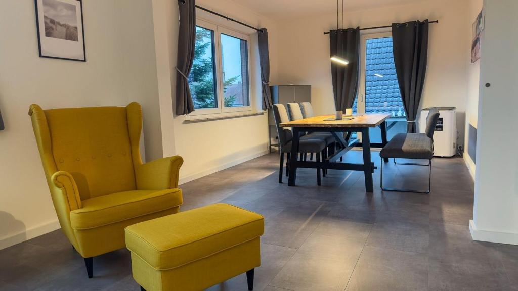 ein Wohnzimmer mit einem Tisch und einem gelben Stuhl in der Unterkunft Strandnahe Ferienwohnung Nordsee Oase Whg. 1 in Cuxhaven