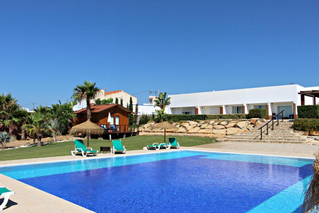 a swimming pool with chairs and a building at Guesthouse Quinta Saleiro in Olhão