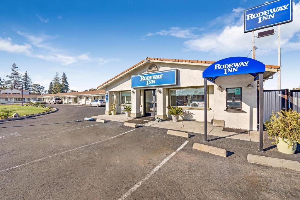 a dealership with blue signs in a parking lot at Rodeway Inn Stockton Highway 99 in Stockton