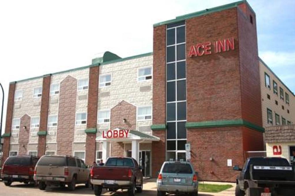 ein großes Backsteingebäude mit Autos auf einem Parkplatz in der Unterkunft Ace Inn in Fort McMurray