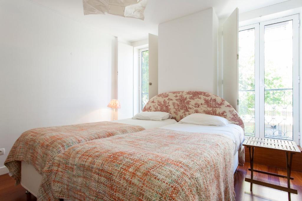 um quarto com uma cama com um cobertor e janelas em ALTIDO Belem Burgundy em Lisboa