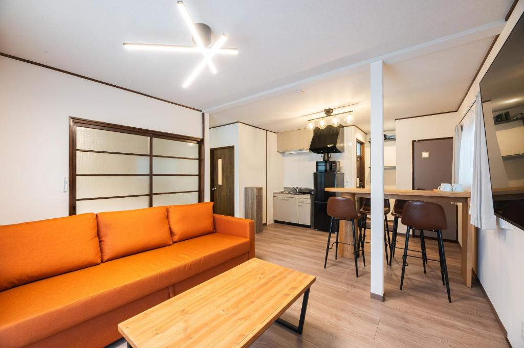 a living room with an orange couch and a kitchen at Ojanse博多 in Fukuoka